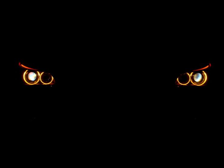 the eyes of an evil looking person in the dark with glowing orange and white lights