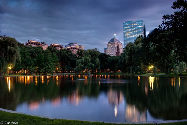 the city skyline is lit up at night, and reflecting in the water's surface