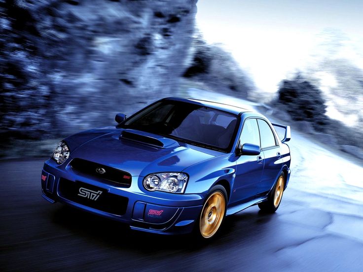 a blue car driving down a road with mountains in the background