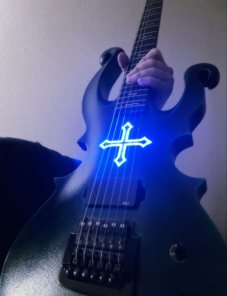 a guitar with a glowing cross on it's neck is shown in front of a white wall