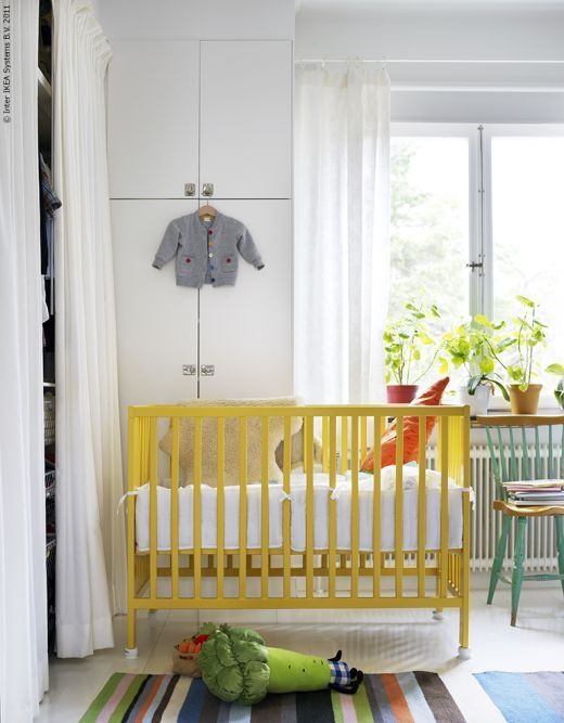 a baby's room with a yellow crib and colorful rugs on the floor