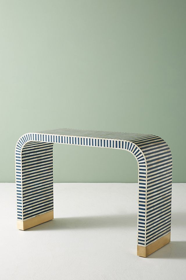 a white and blue bench sitting on top of a table next to a green wall