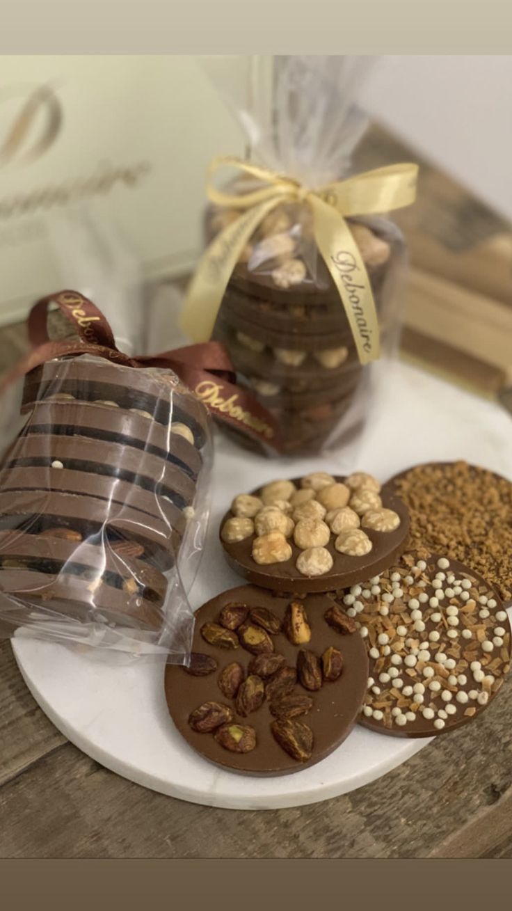 a white plate topped with chocolate covered cookies next to a bag of nuts and almonds