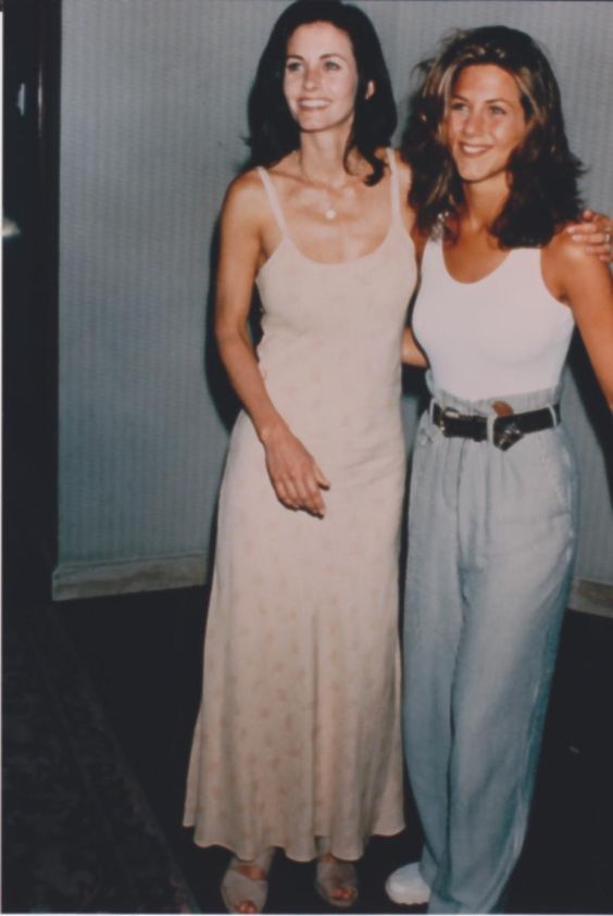 two women standing next to each other in front of a wall with white walls and carpet