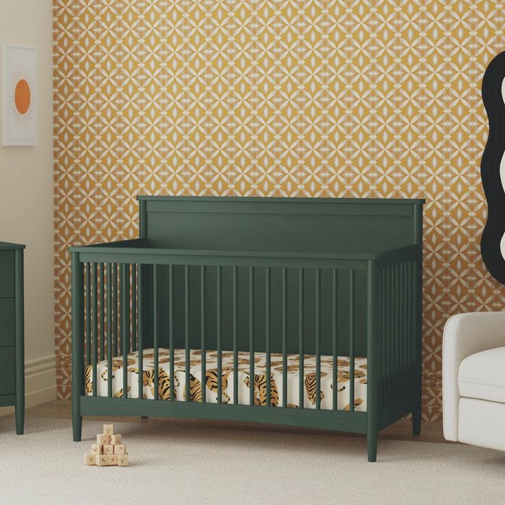 a green crib in front of a wall with gold and white designs on it