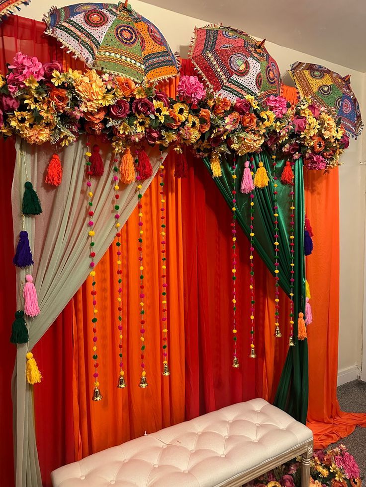 an orange and green decorated stage with flowers, umbrellas and tassels on it