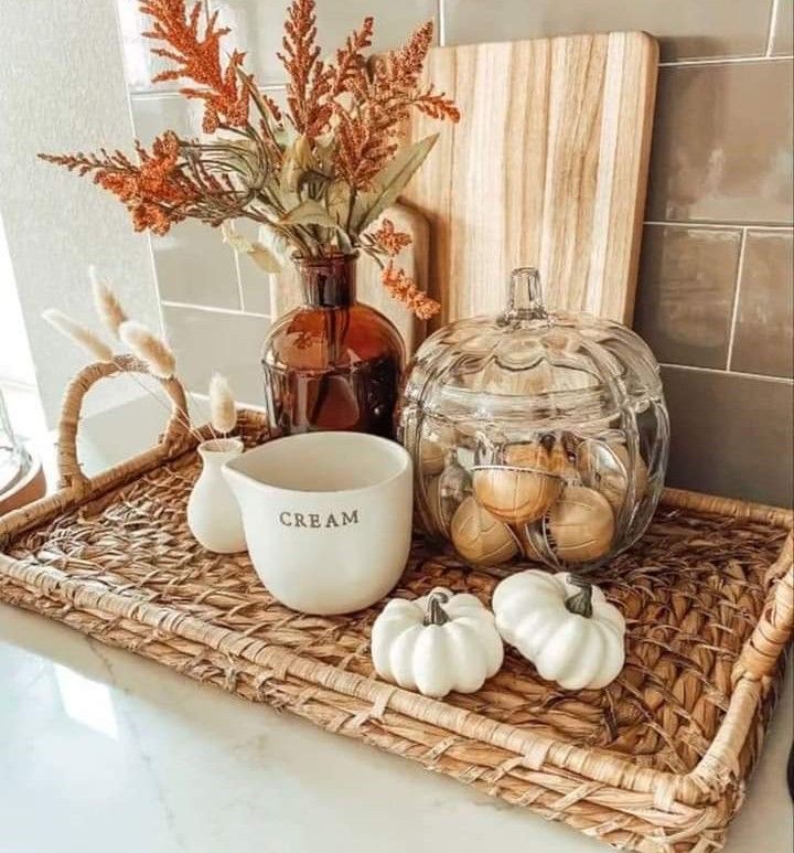 a wicker tray topped with pumpkins and other fall decorating items on top of a counter