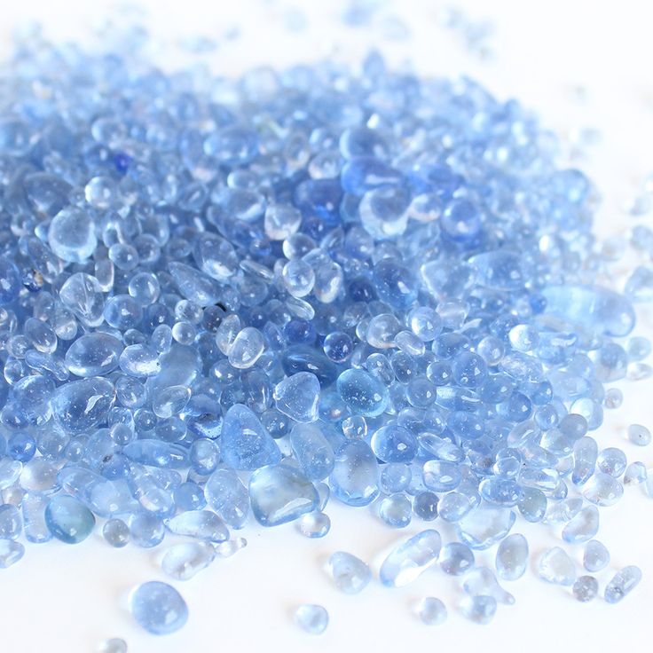 blue glass beads are scattered on a white surface, as if they were water droplets