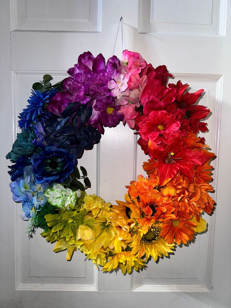 a rainbow colored flower wreath hangs on the front door with white doors and wooden paneling