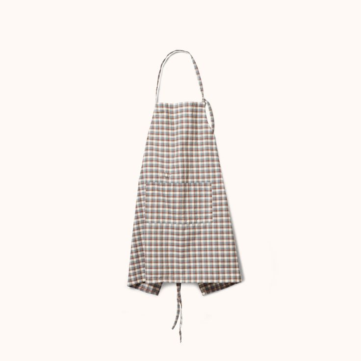 a brown and white checkered apron hanging from a string on a white wall,