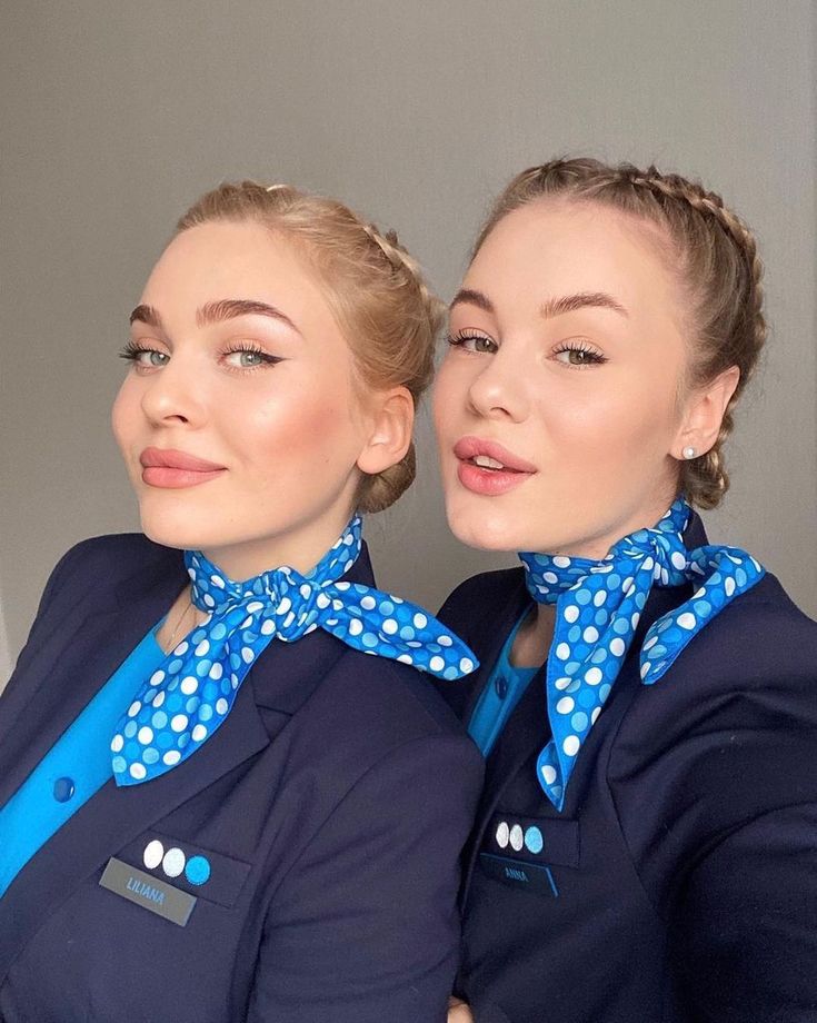 two women in blue uniforms with polka dots on their collars are posing for the camera