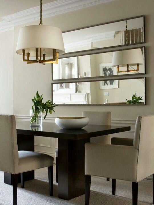 a dining room table with chairs and a mirror on the wall in front of it