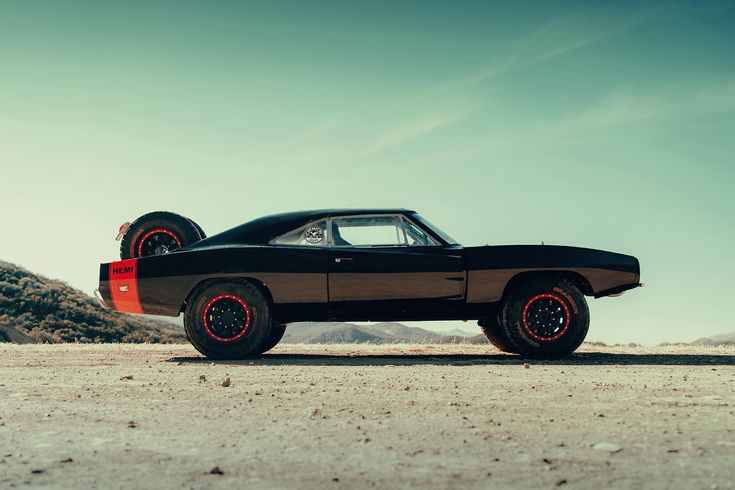 a black car with red rims parked in the desert