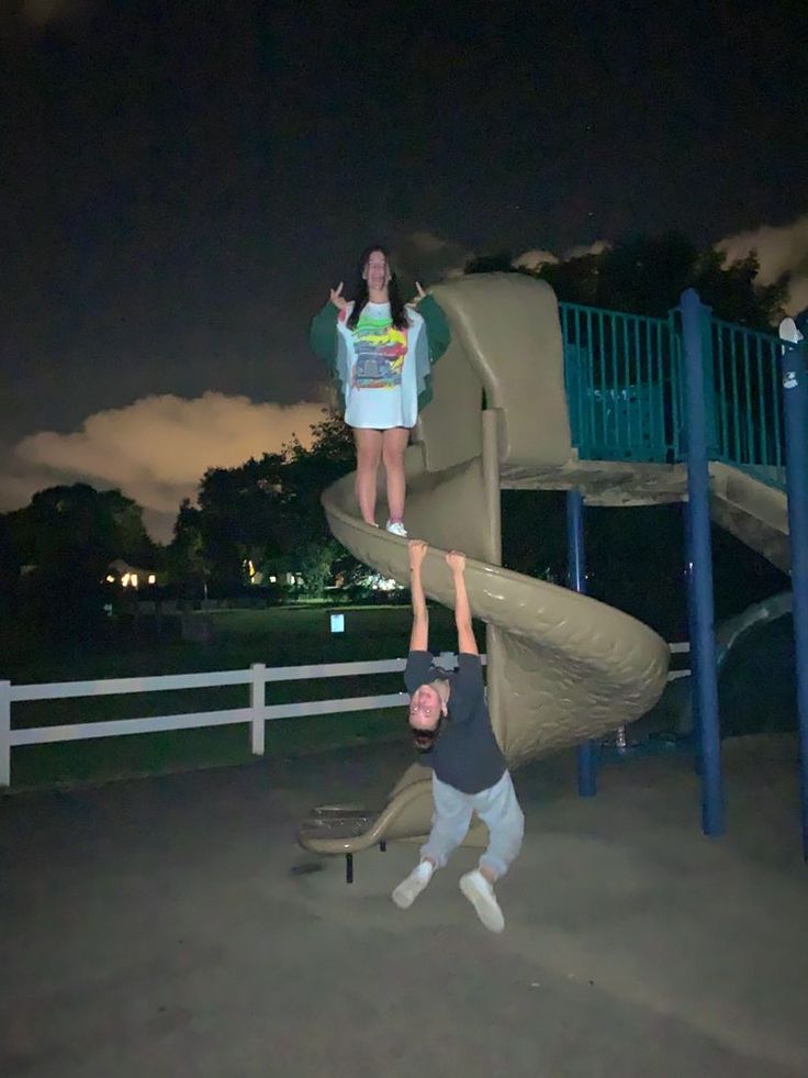 two people doing tricks on a playground slide