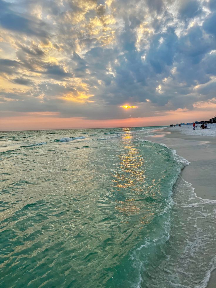 the sun is setting over the water at the beach