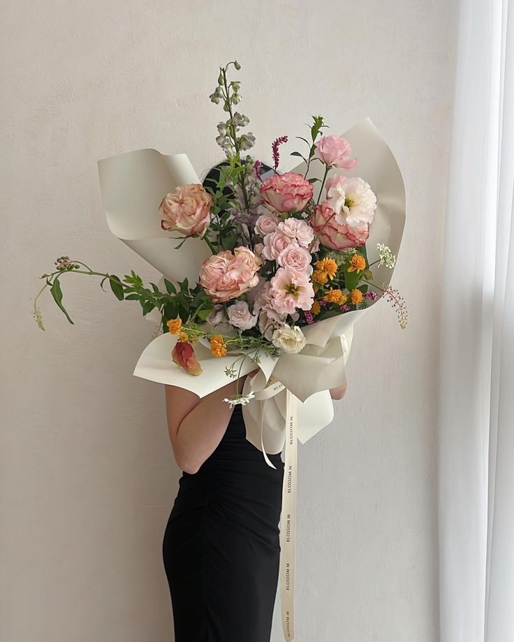 a woman in a black dress holding a bouquet of flowers