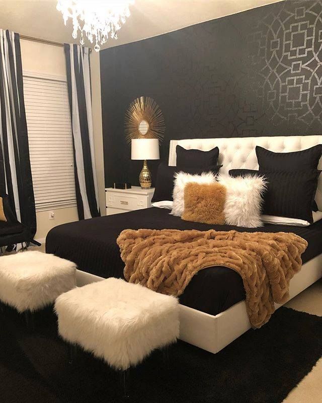 a bedroom with black and white walls, fur rugs on the floor and a large bed