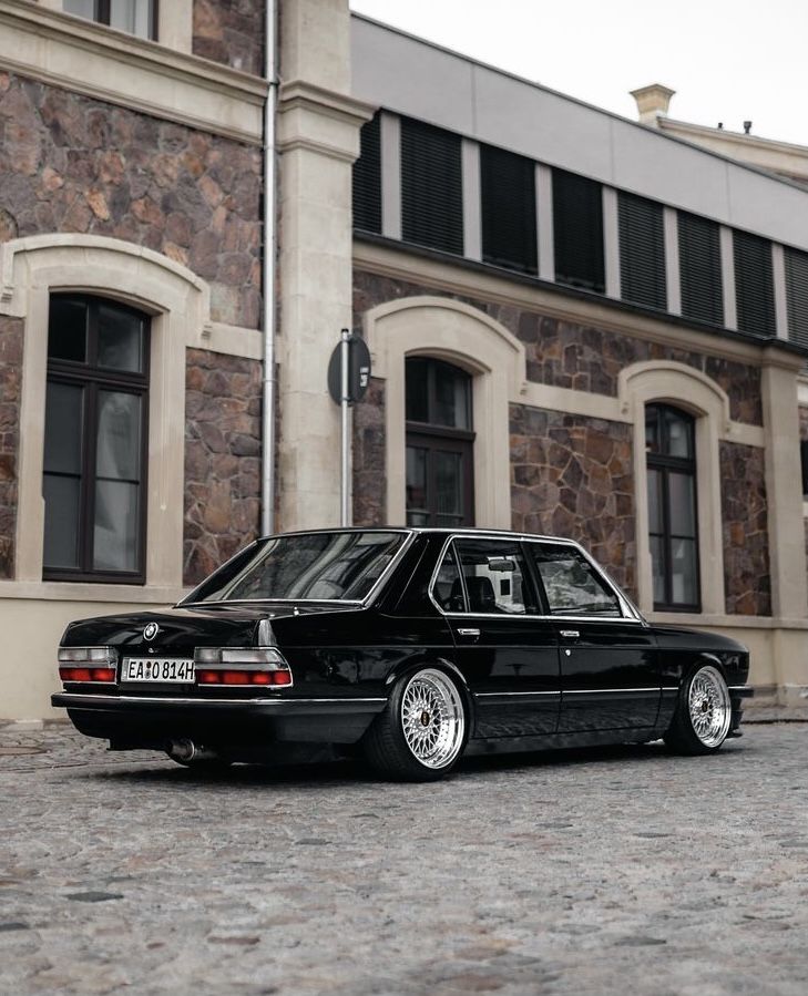 a black car parked in front of a stone building with windows and doors on it