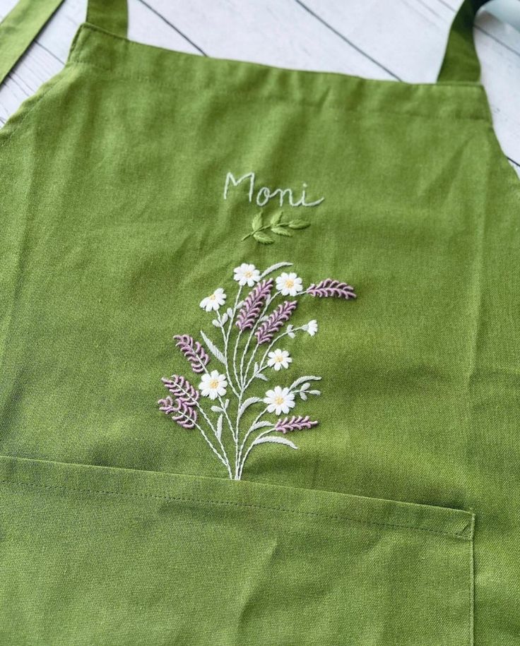 a green apron with flowers embroidered on it