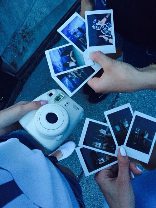 people holding polaroid photos and taking pictures on the ground with an old fashioned camera