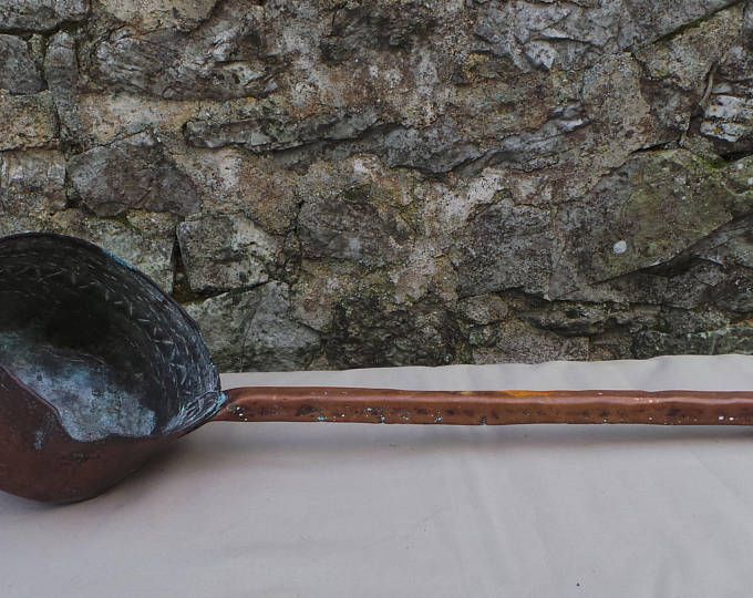 an old wooden spoon sitting on top of a table next to a rock covered wall