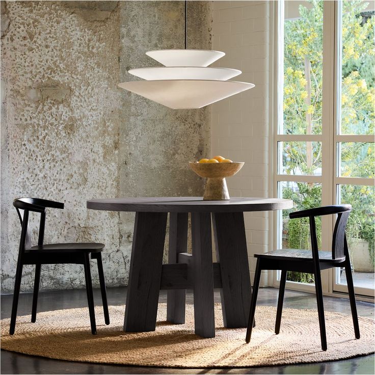 a dining room table with two chairs and a bowl of fruit on the table next to it