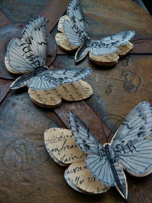 three butterflies with writing on them sitting on top of a piece of wood and paper