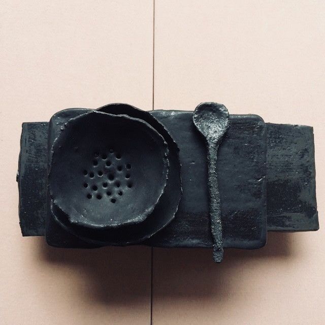 a metal object with a spoon on top of it next to a tile floor and wall