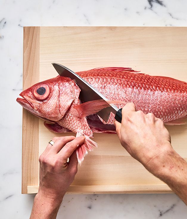 a person cutting up a fish with a knife