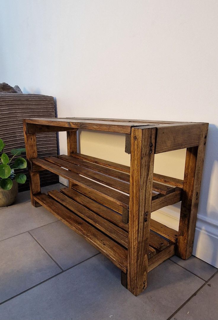 a wooden bench sitting on top of a tile floor next to a potted plant