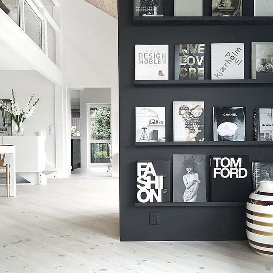 a black and white living room with pictures on the wall next to a vase filled with flowers