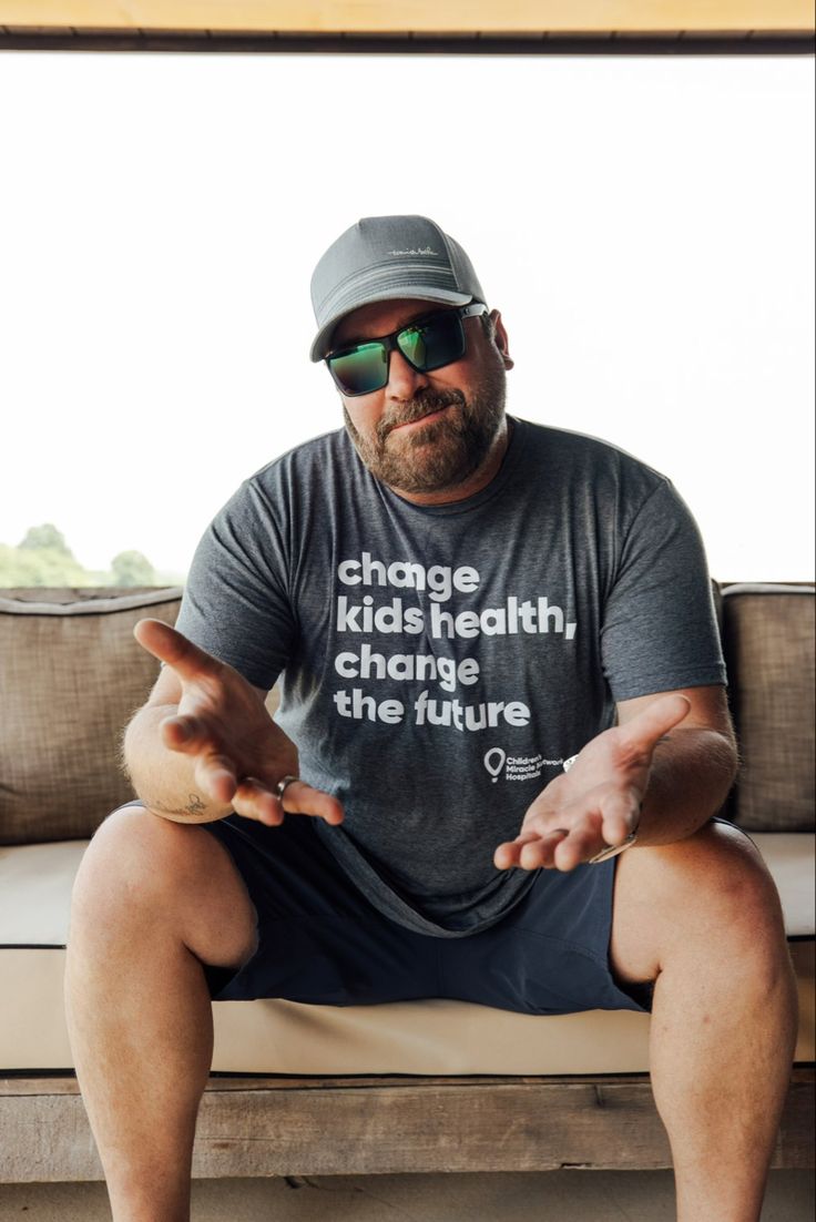 a man sitting on top of a couch wearing sunglasses and holding something in his hand