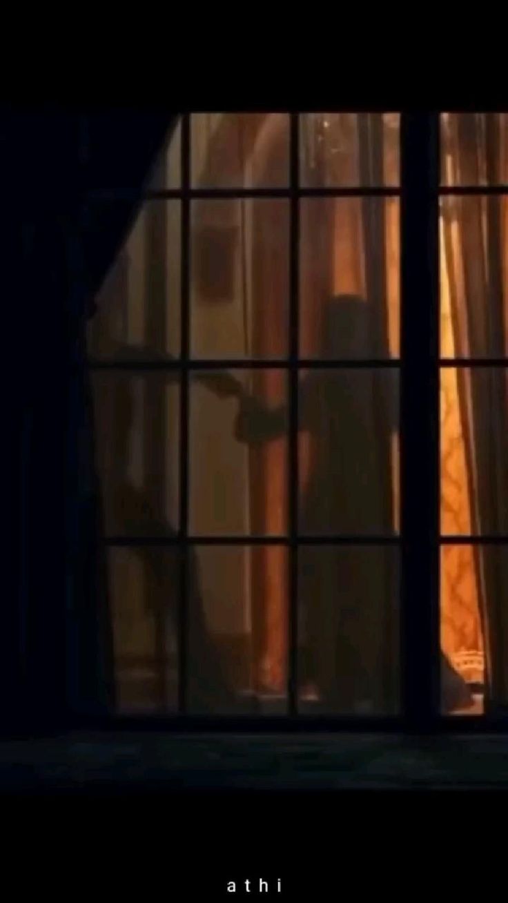 the silhouette of a person standing in front of a window with curtains on both sides