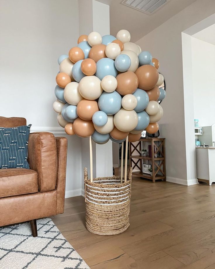 a balloon tree in a living room filled with blue, beige and white balloons on a wooden floor