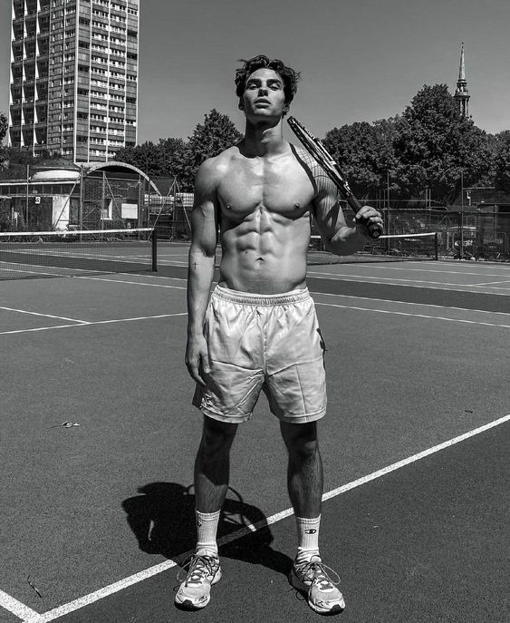 a shirtless man holding a tennis racquet on top of a tennis court