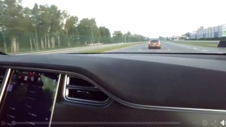 the dashboard of a car on a road with trees and buildings in the back ground