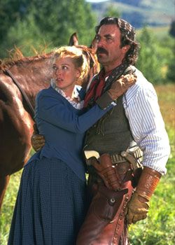 a man and woman standing next to a horse