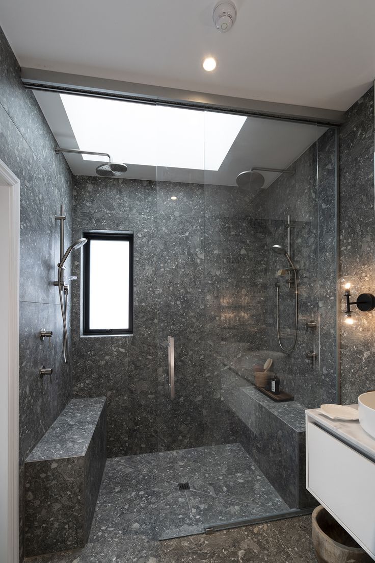 a bathroom with a large walk in shower next to a sink and toilet under a skylight