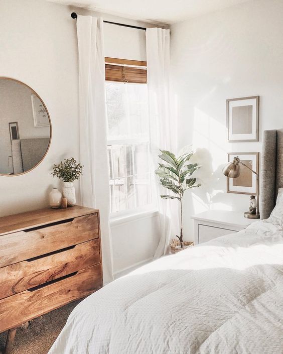 a bedroom with a bed, dresser and mirror in the corner next to a window