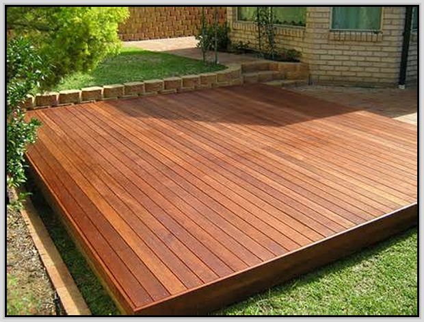 a wooden deck in front of a brick house