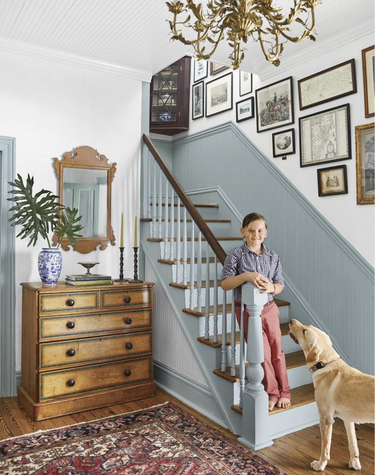 a boy and his dog are standing at the bottom of stairs in front of a staircase