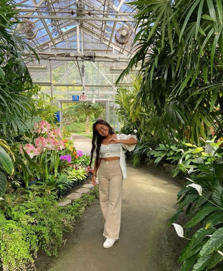 a woman standing in a greenhouse with lots of plants