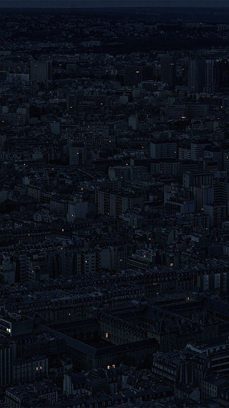 an aerial view of a city at night with the moon in the sky and buildings lit up