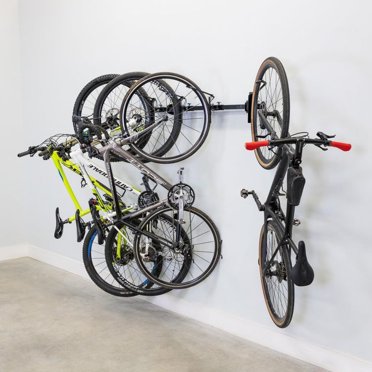 two bikes are hanging on the wall and one is holding it's bike rack