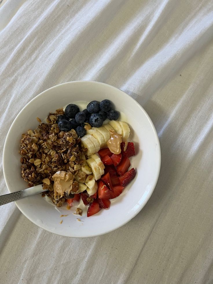 a bowl filled with granola, fruit and yogurt next to a spoon