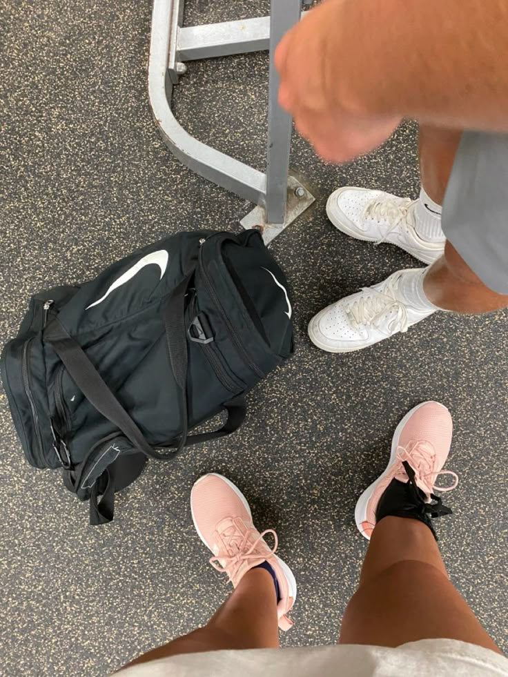 two people standing next to each other in front of a gym bag and exercise equipment