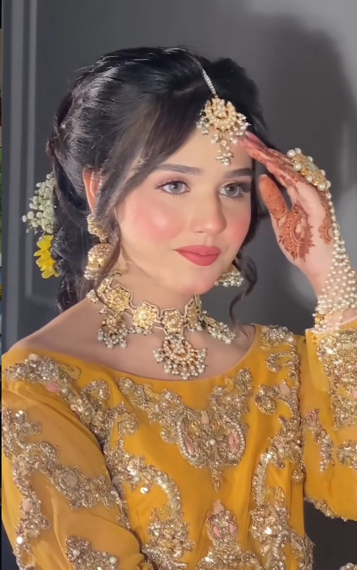 a woman in a yellow dress with jewelry on her head