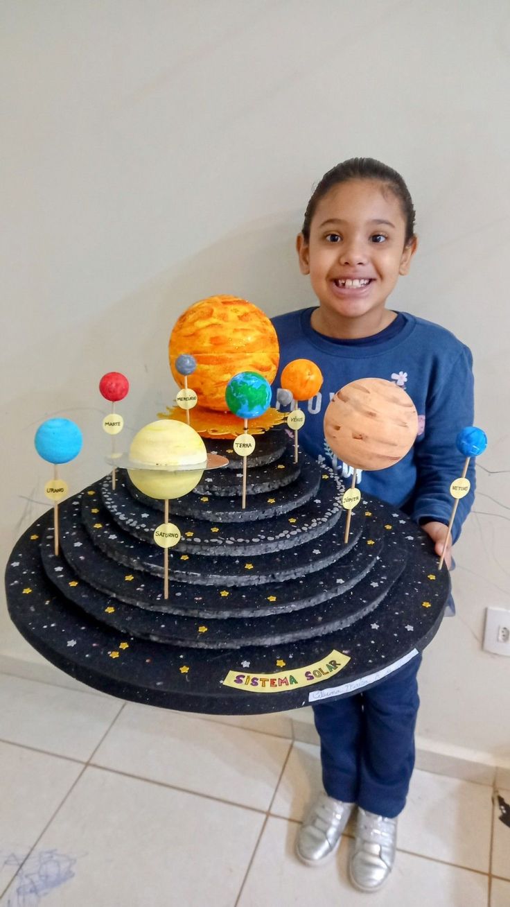 a young boy is holding up a model of the solar system with planets on it