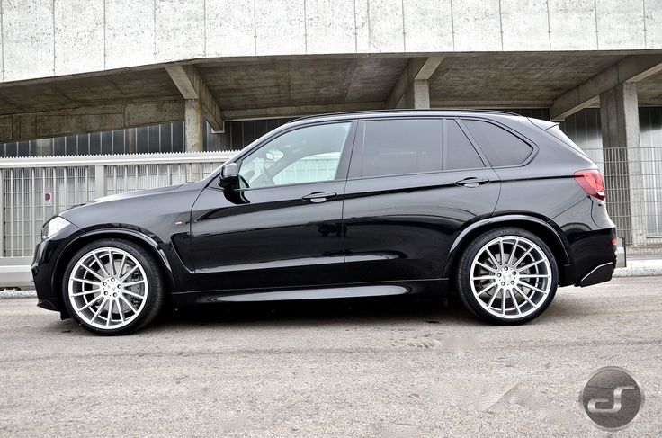 a black car parked in front of a building with white rims and chrome wheels