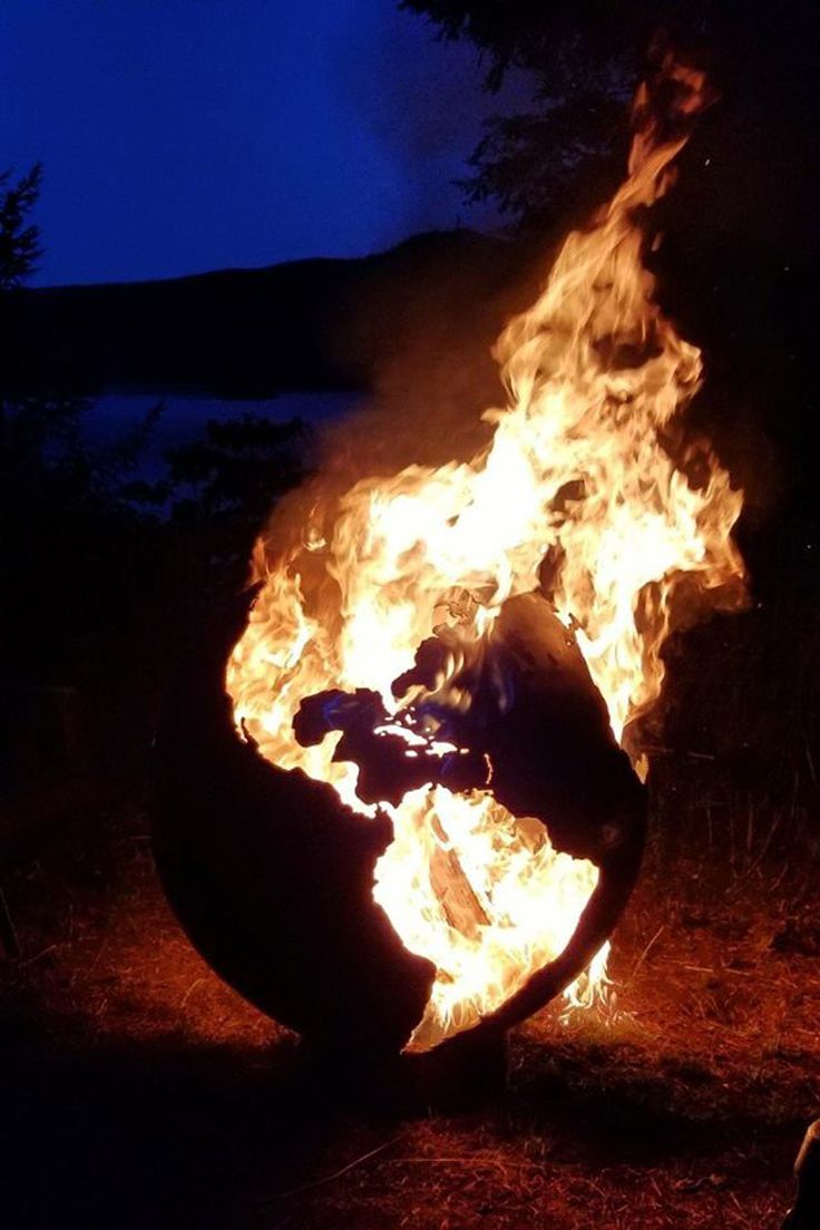 a large fire pit sitting in the middle of a field with lots of flames coming out of it